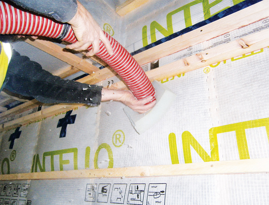 Cellulose insulation is pumped into the timber frame walls
